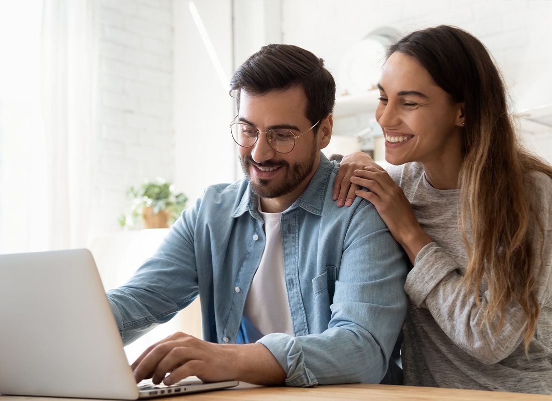 Service Center - Smiling Millennial Couple Using Laptop and Looking at Screen at Home